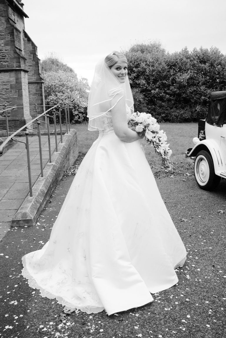Photo of classic bridal pose by JD Photography (Isle of Wight). Bride in full wedding dress turning her head.