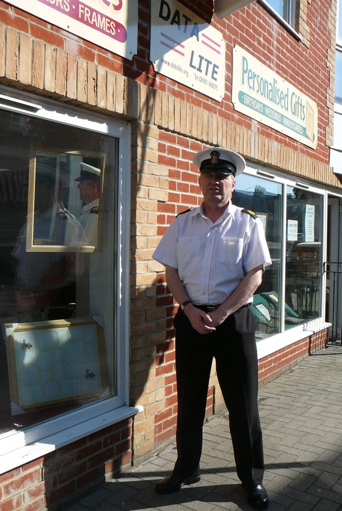 John D Henry of JD Photography in RN uniform, outside Datalite Frame shop in Ryde, Isle of Wight.